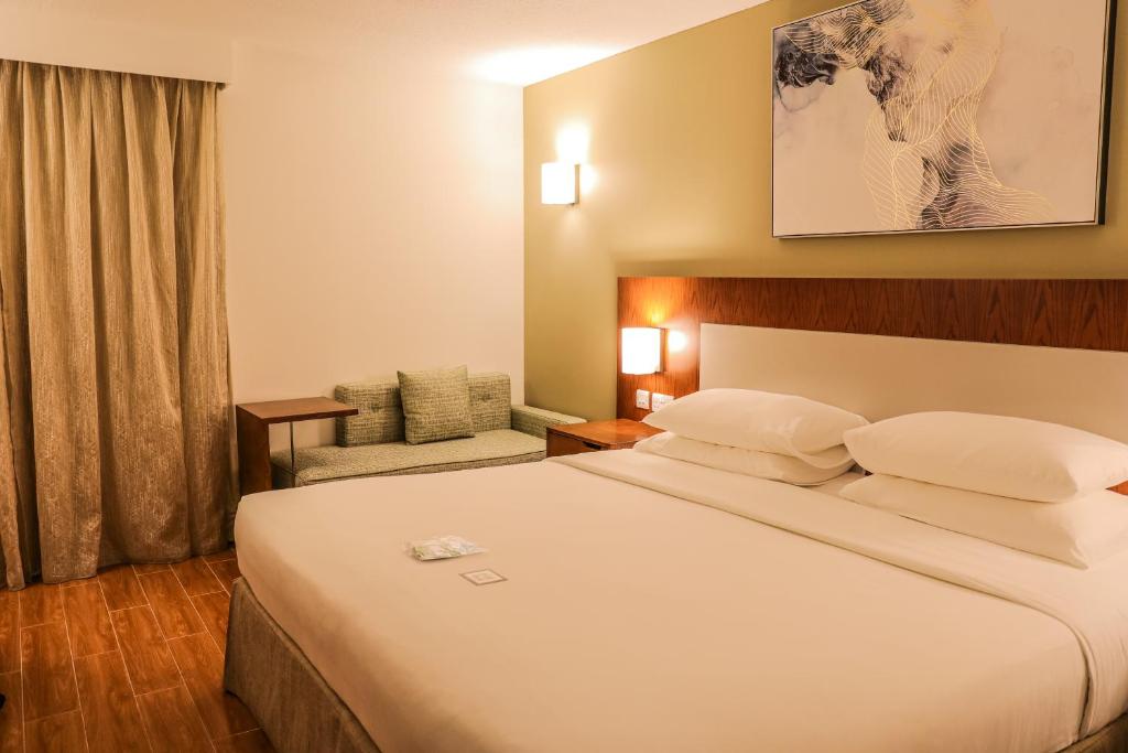 a hotel room with a large bed and a chair at Dhafra Beach Hotel in Jebel Dhanna