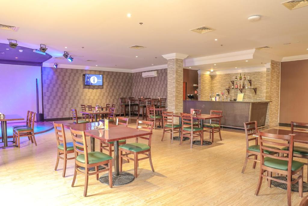 a restaurant with wooden tables and chairs and a bar at Dhafra Beach Hotel in Jebel Dhanna