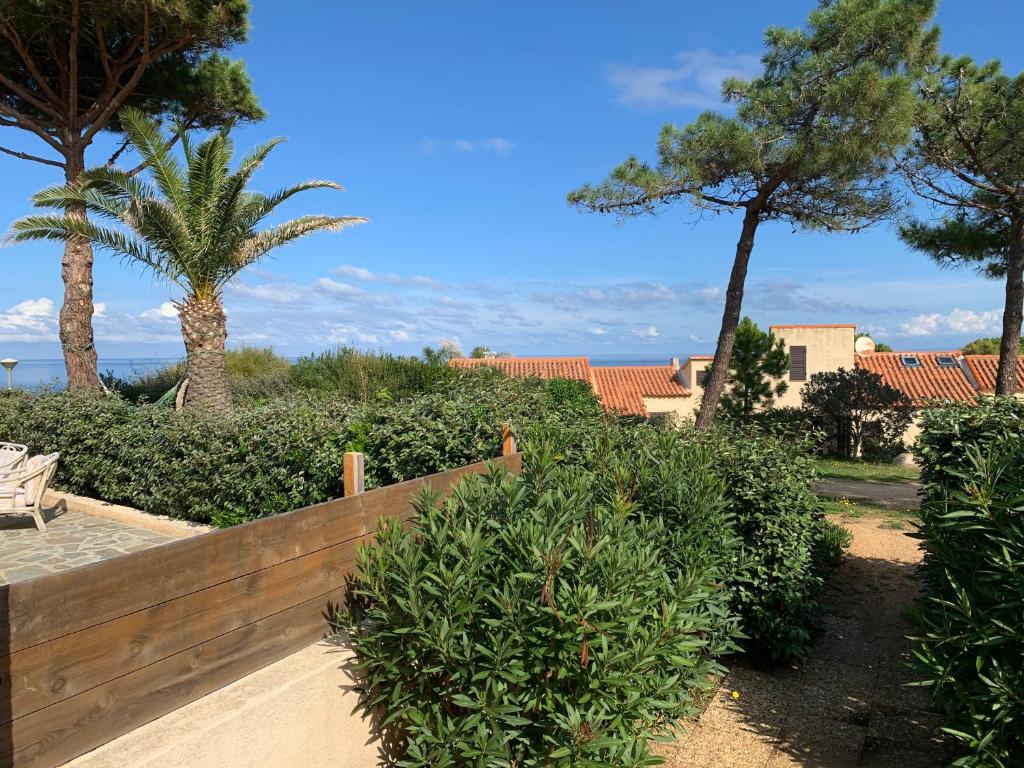 una valla de madera frente a algunos arbustos y árboles en Mini villa climatisée - Vue mer - Mer à 50 m - Jardin et 2 terrasses 300 m2, en Lumio