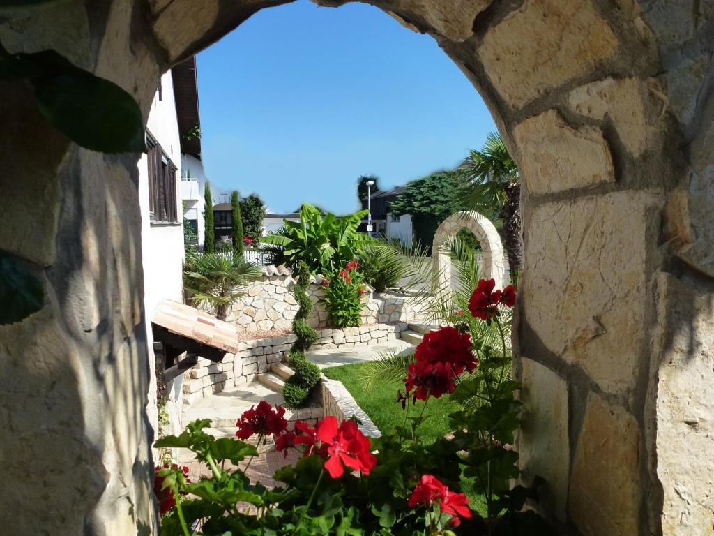 Blick auf den Garten durch ein Steinfenster in der Unterkunft Apartmenthaus Casa Palma in Bühl