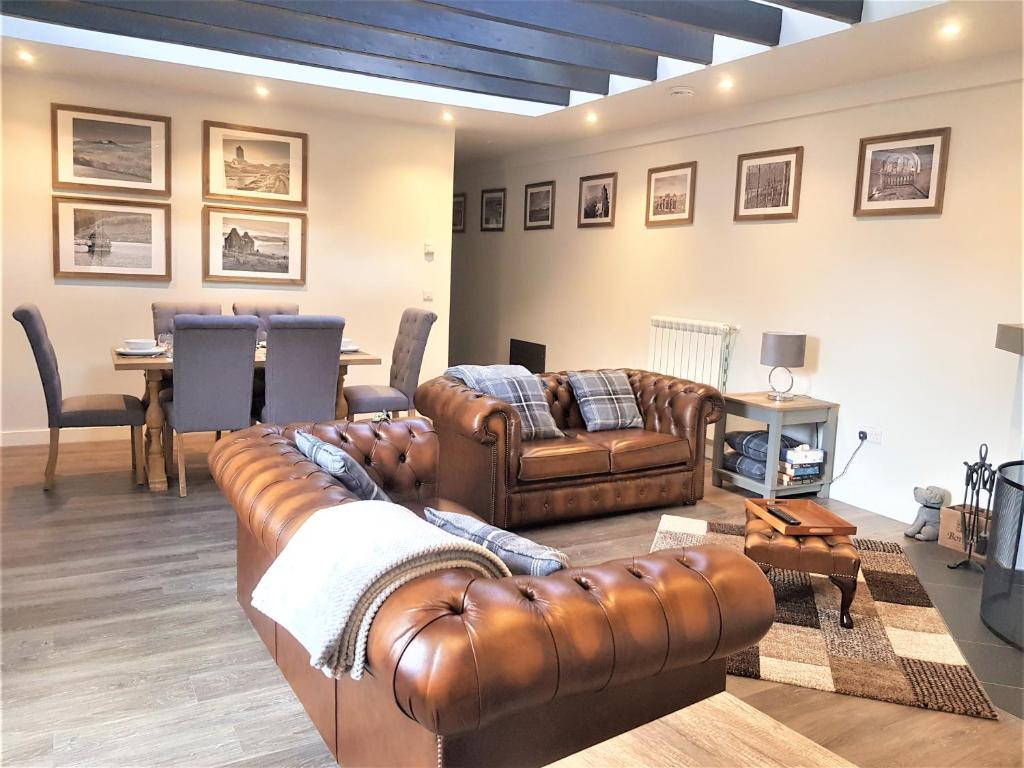 a living room with two leather couches and a table at Hunters Holiday Cottage in Saint Boswells