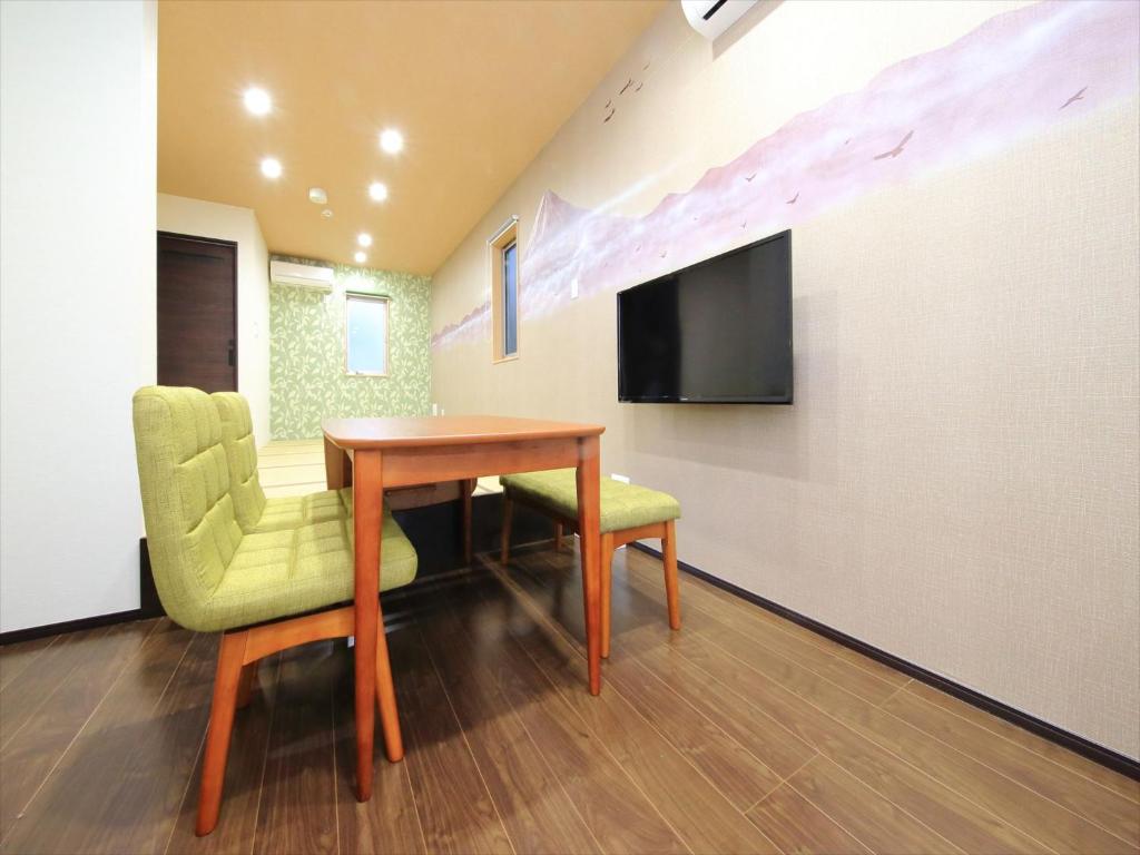 Habitación con mesa, 2 sillas y TV. en COTO Tokyo Nakano, en Tokio