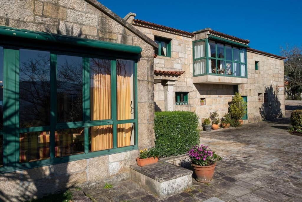 una casa in pietra con finestre verdi e balcone di Villa Ponte Bora a Pontevedra