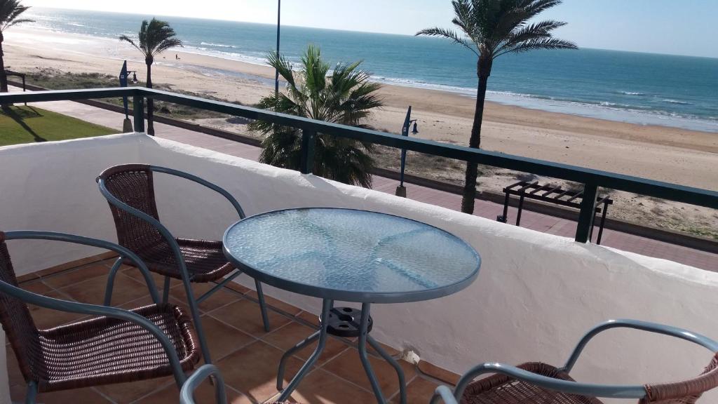 - stół i krzesła na balkonie z widokiem na plażę w obiekcie Primera linea de playa "Barrosamar" w mieście Chiclana de la Frontera