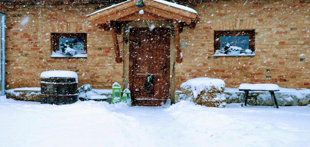 Una tormenta de nieve frente a una casa de ladrillo en Míves Vendégház, en Pogány