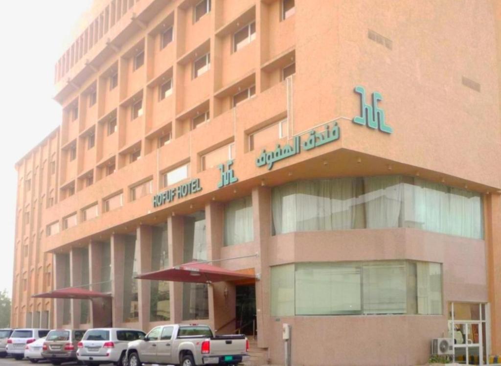 duży budynek z samochodami zaparkowanymi przed nim w obiekcie Hofuf Hotel w mieście Al-Hufuf