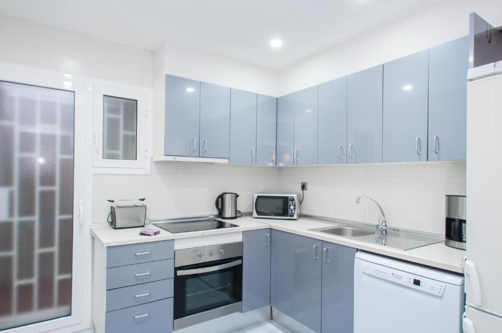 una cucina con armadi blu e lavandino di Autèntic Arc de Triomf Apartment a Barcellona