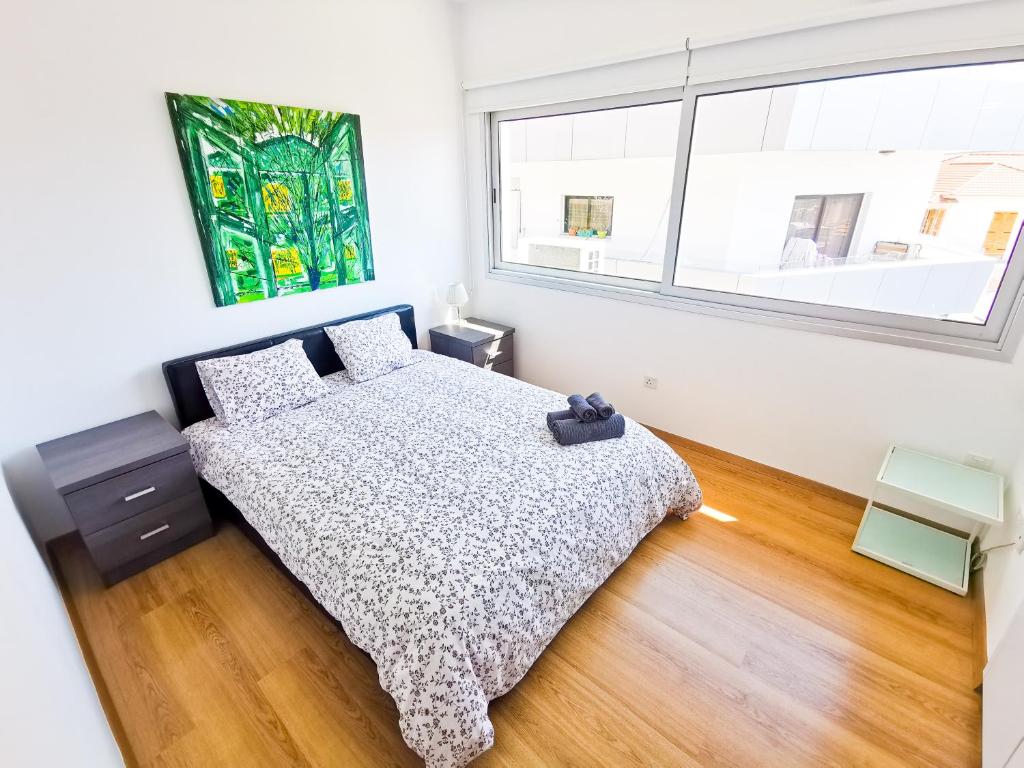 Un dormitorio con una cama y una ventana grande. en Daze Off Central Apartment, 300m to the Finikoudes Beach, en Lárnaca