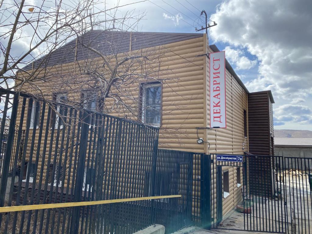 a house behind a fence with a sign on it at Хостел Декабрист in Chita