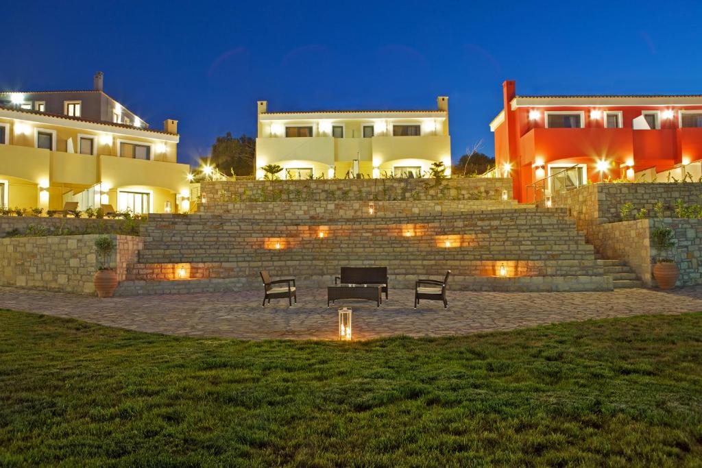a park with benches in front of buildings at night at Carme Villas in Adelianos Kampos