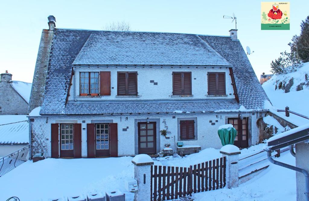 Biały dom z płotem w śniegu w obiekcie La Cascade Fleurie w mieście Saint-Genès-Champespe