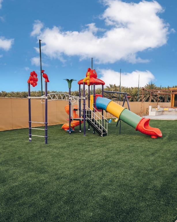 a playground with a slide on a grass field at Seven Elements Resort in Ras al Khaimah