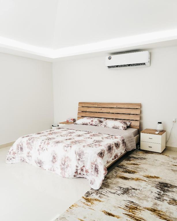 a white bedroom with a bed with a wooden headboard at Seven Elements Resort in Ras al Khaimah