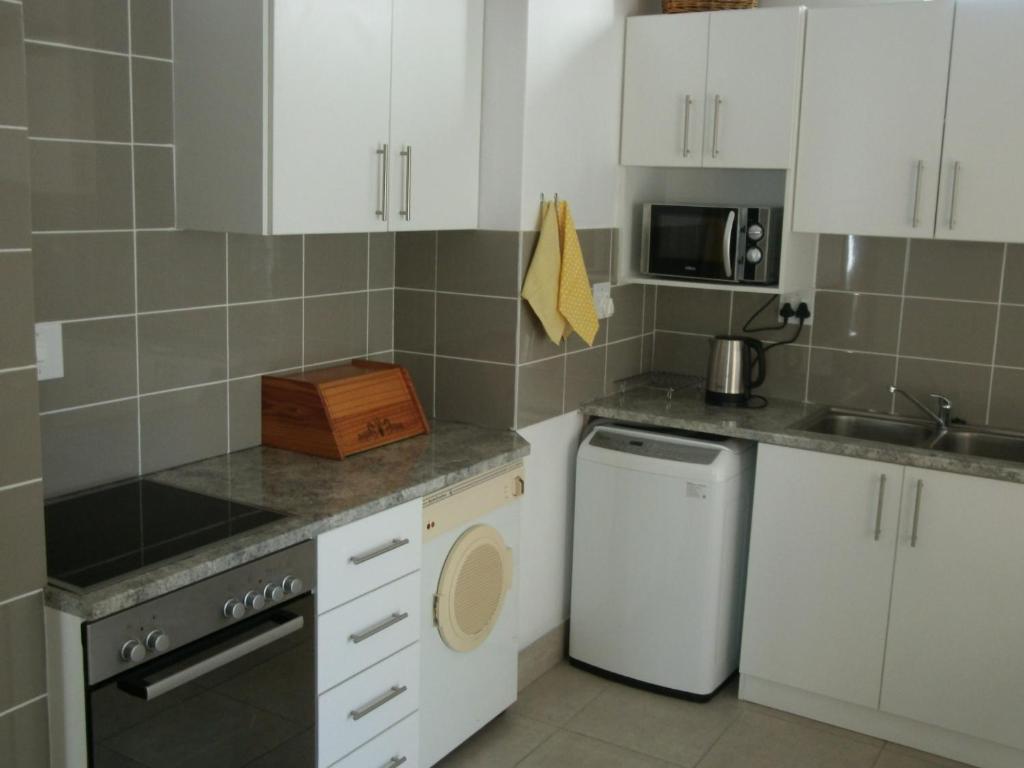 a kitchen with white cabinets and a washer and dryer at Casa Bianco in Montagu