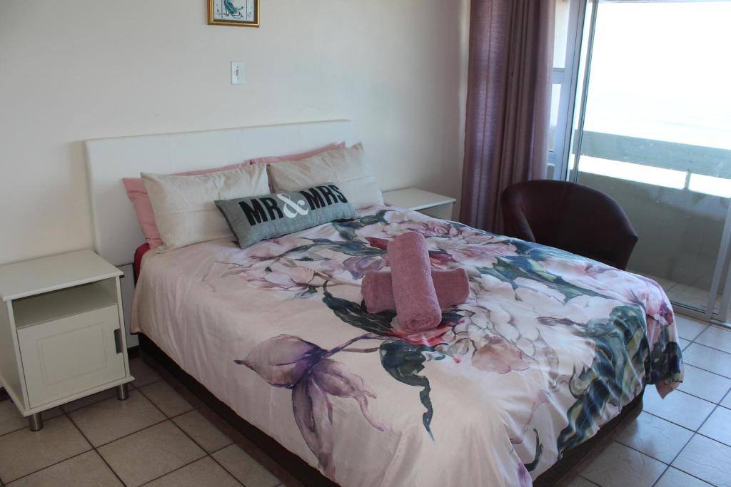 1 dormitorio con 1 cama con colcha de flores en Stella Maris 144 en Amanzimtoti