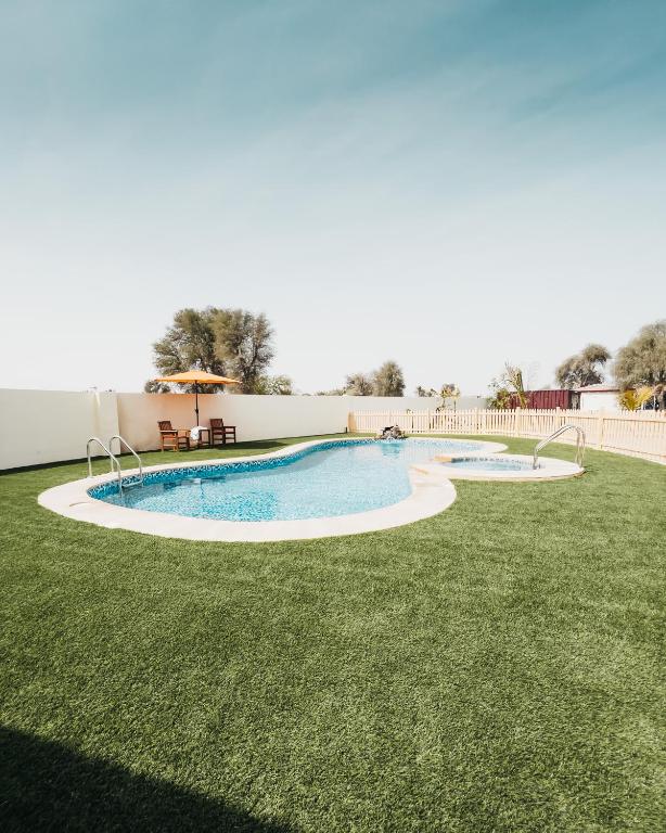 a swimming pool in a yard with grass at Seven Elements Resort in Ras al Khaimah