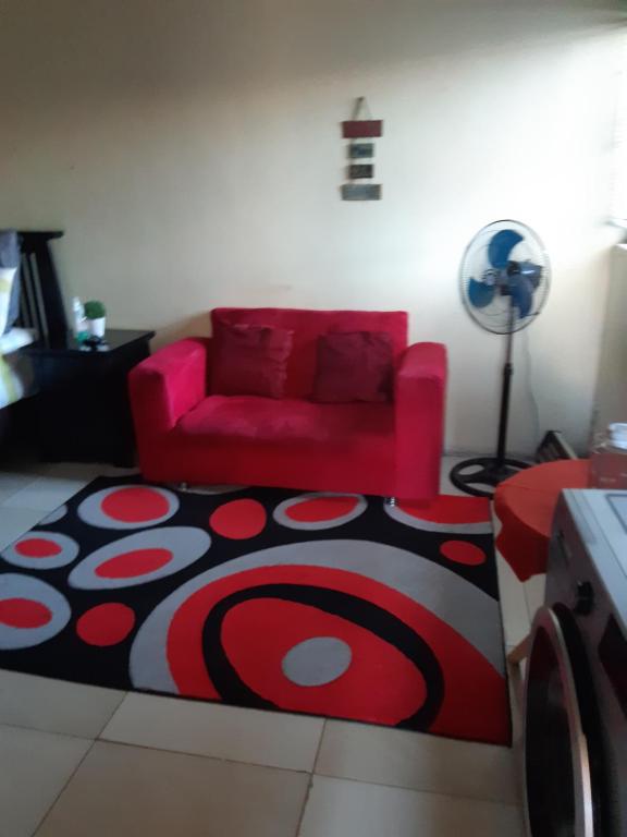 uma sala de estar com um sofá vermelho e um tapete em Lapa la Bakgatlha guest house em Joanesburgo