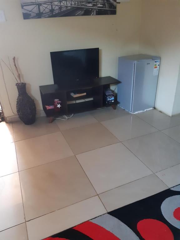 uma sala de estar com uma televisão e um frigorífico em Lapa la Bakgatlha guest house em Joanesburgo