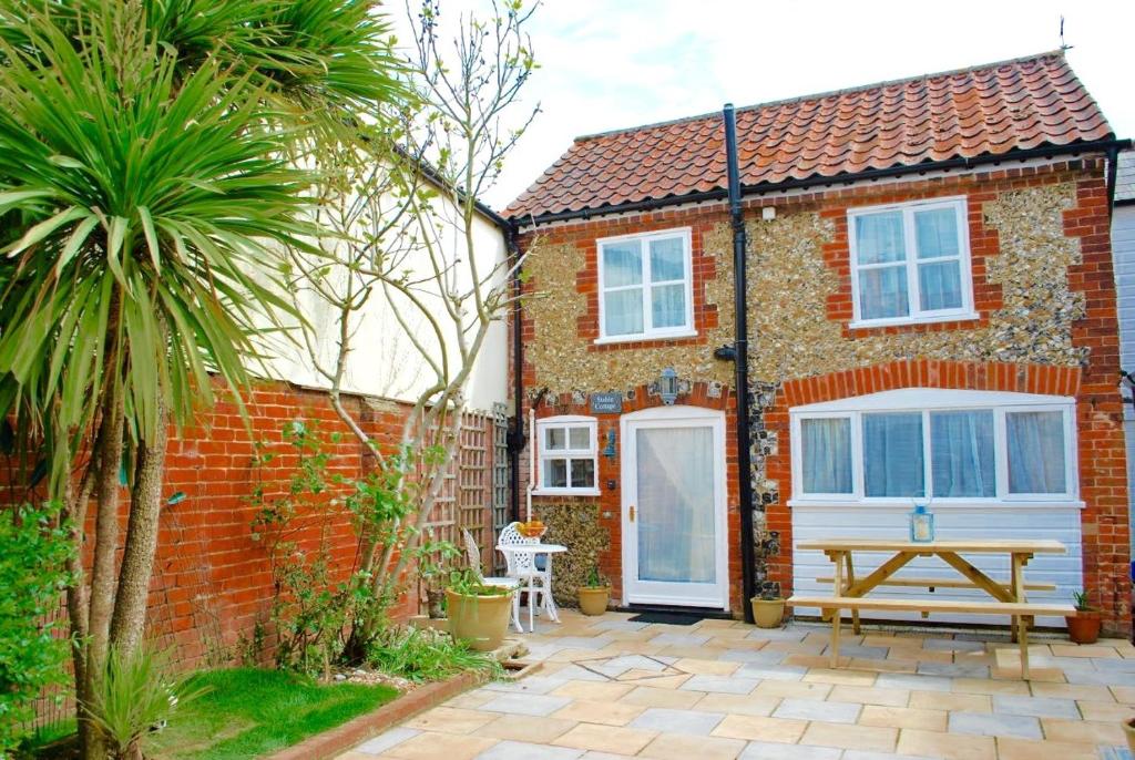 a brick house with a picnic table in front of it at Romantic Flint Cottage on the Suffolk Coast in Saxmundham
