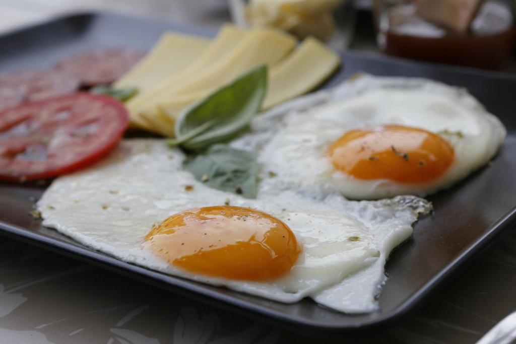 two eggs on a plate with cheese and tomatoes at Kisas Loft By Pinch in Pakoštane