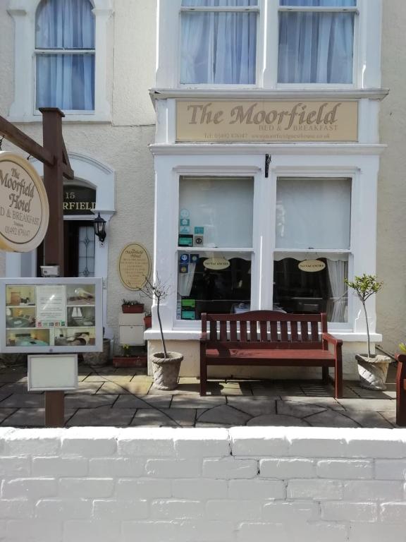 um edifício com um banco em frente a uma loja em Moorfield Hotel em Llandudno