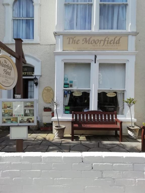 a building with a bench in front of a store at St Davids & Moorfield Hotels Chapel Street in Llandudno