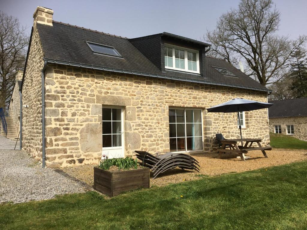 een stenen huis met een tafel en een paraplu bij Gites de Kermoel, Belle Île in Kernascléden