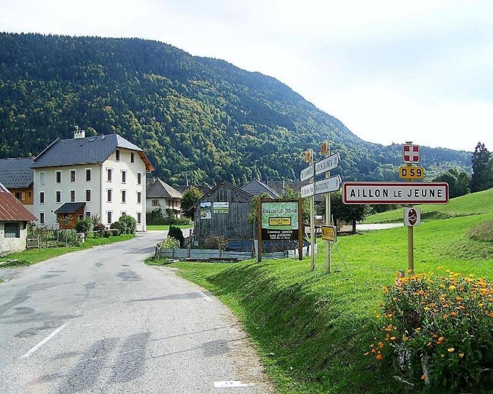 a village with a street sign and a mountain at Hôtel du Soleil in Aillon-le-Jeune