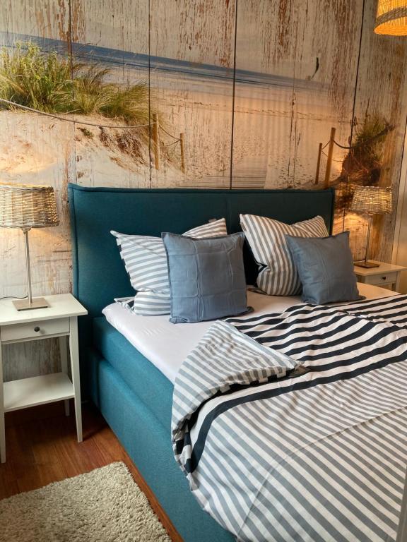ein blaues Bett mit gestreifter Bettwäsche und Kissen darauf in der Unterkunft Ferienhäuser Fischerweg in Dornumersiel