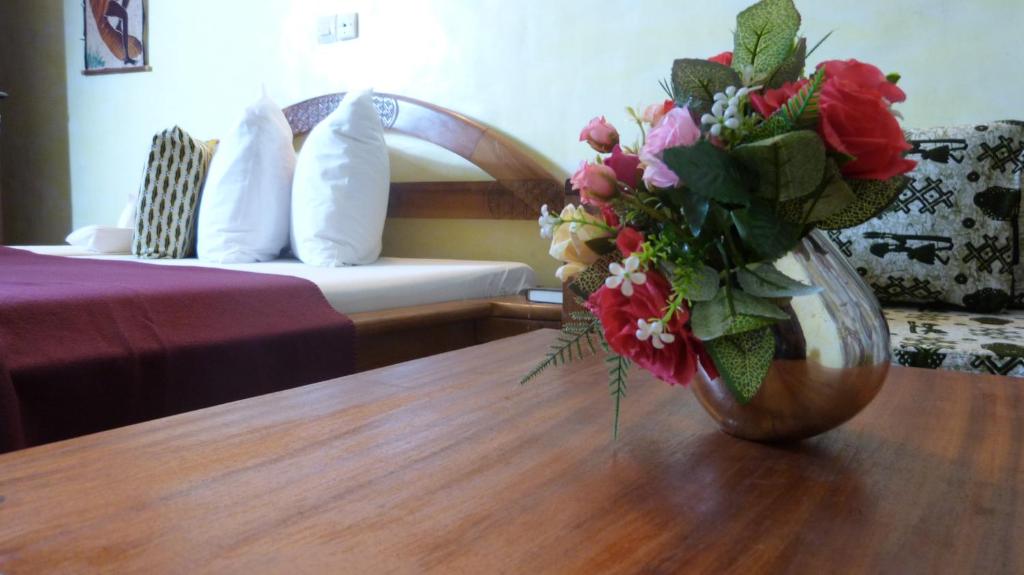 un vase de fleurs assis sur une table dans une chambre d'hôtel dans l'établissement Hotel Madou Grand Bassam, à Grand-Bassam