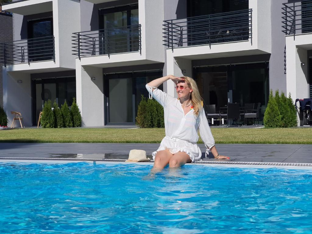 a woman sitting on the edge of a swimming pool at AZURE Apartament Pobierowo in Pobierowo