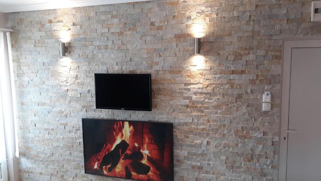 a brick wall with a fireplace with a tv on it at Apartman "Vienna" in Soko Banja