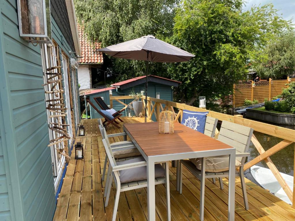 einen Holztisch und Stühle auf einer Terrasse mit einem Sonnenschirm in der Unterkunft Ferienhaus Grosses Meer mit Boot in Südbrookmerland
