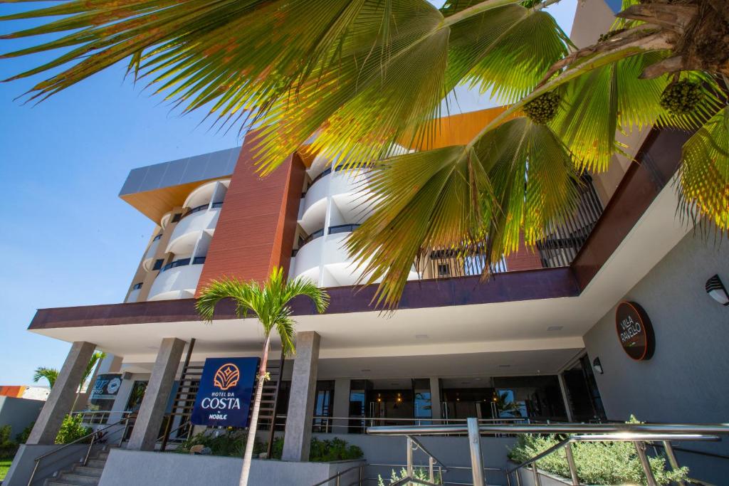 un bâtiment avec des palmiers en face de celui-ci dans l'établissement Hotel da Costa By Nobile, à Aracaju