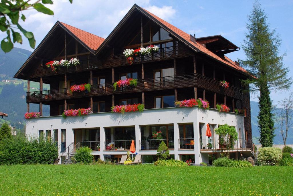 a large wooden house with flowers in front of it at Apart-Garni Innerwiesn in Mayrhofen