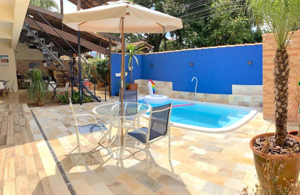 un patio con mesa, sombrilla y piscina en VELINN Pousada Praia do Perequê, en Ilhabela