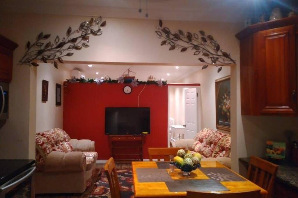 uma sala de estar com uma mesa e uma parede vermelha em Ocho Rios Hideaway em Ocho Rios