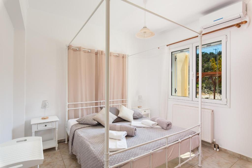 a white bedroom with a canopy bed with a window at Plaque Panoramic SeaView Villa in Chania Town