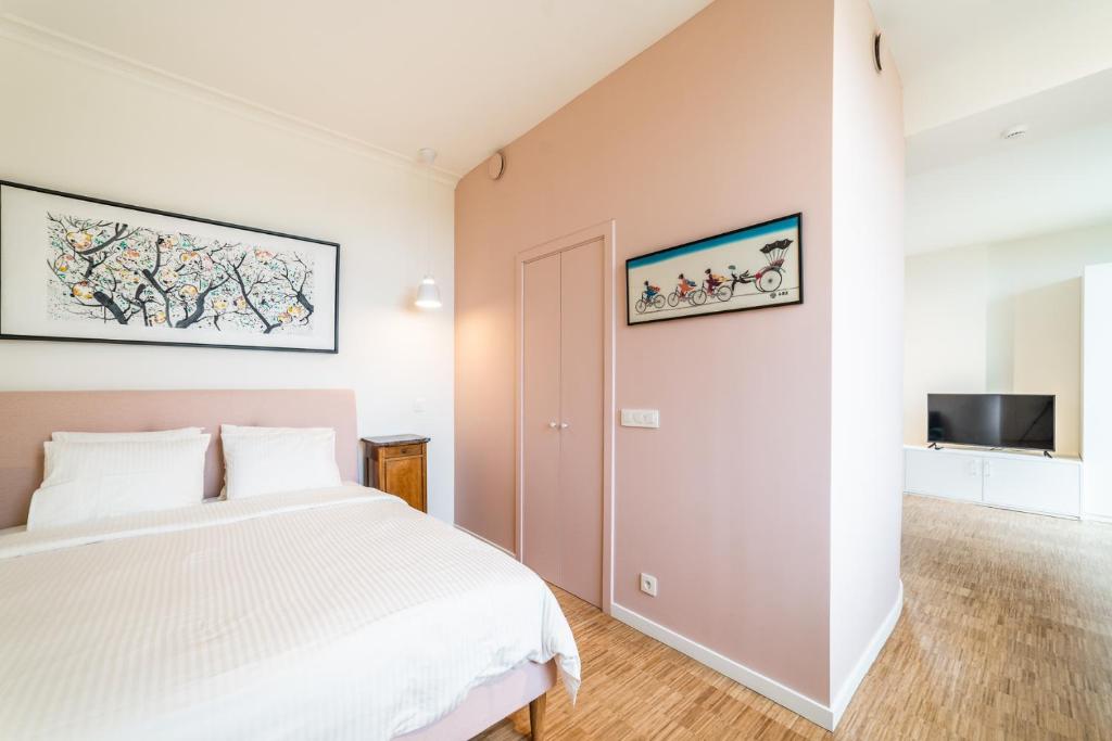 een slaapkamer met een wit bed en een televisie bij La Vista in Tervuren