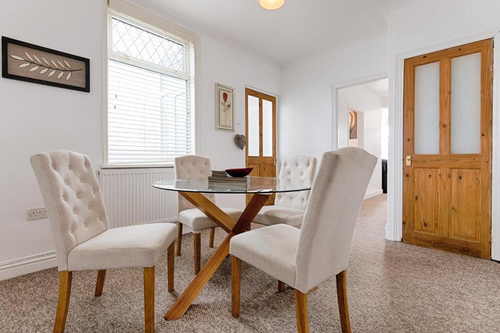 a dining room with a glass table and white chairs at River House with Parking - TV in Every Bedroom! in Loughor