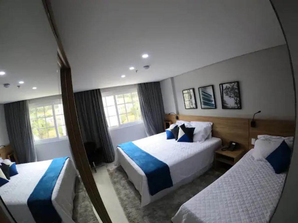um quarto de hotel com duas camas e um espelho em Charmoso Flat em Itaipava, 509 Mangabeiras. em Petrópolis