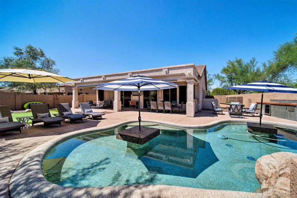 una piscina con sombrillas y sillas y un patio en Tranquil retreat with pool, billiards, putting green, en Scottsdale