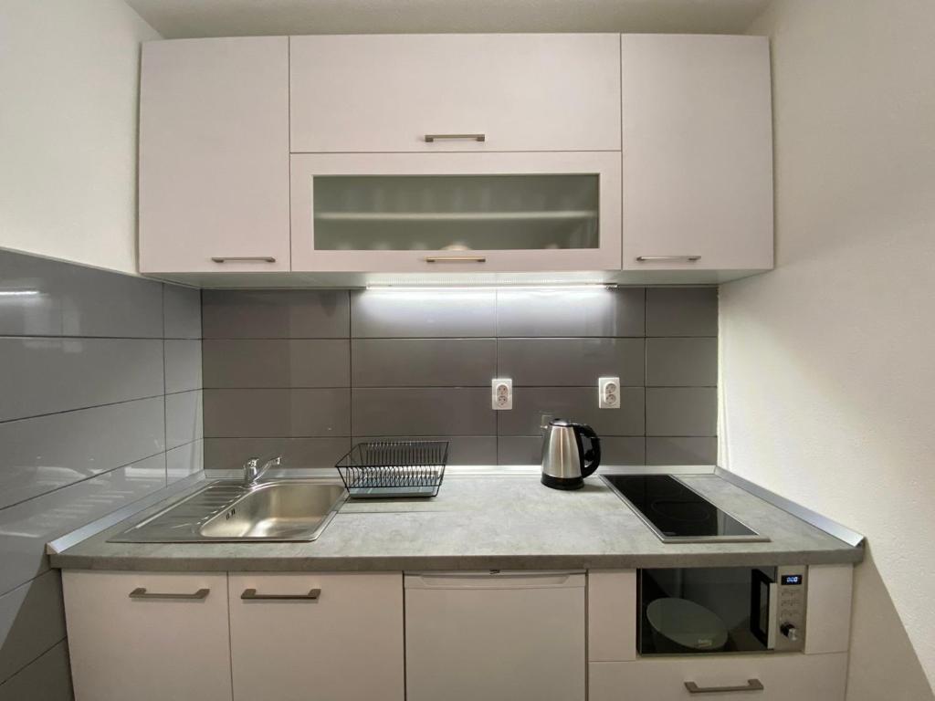 ブルゼーチェにあるBele Staze Kopaonik sの白いキャビネットとシンク付きのキッチン