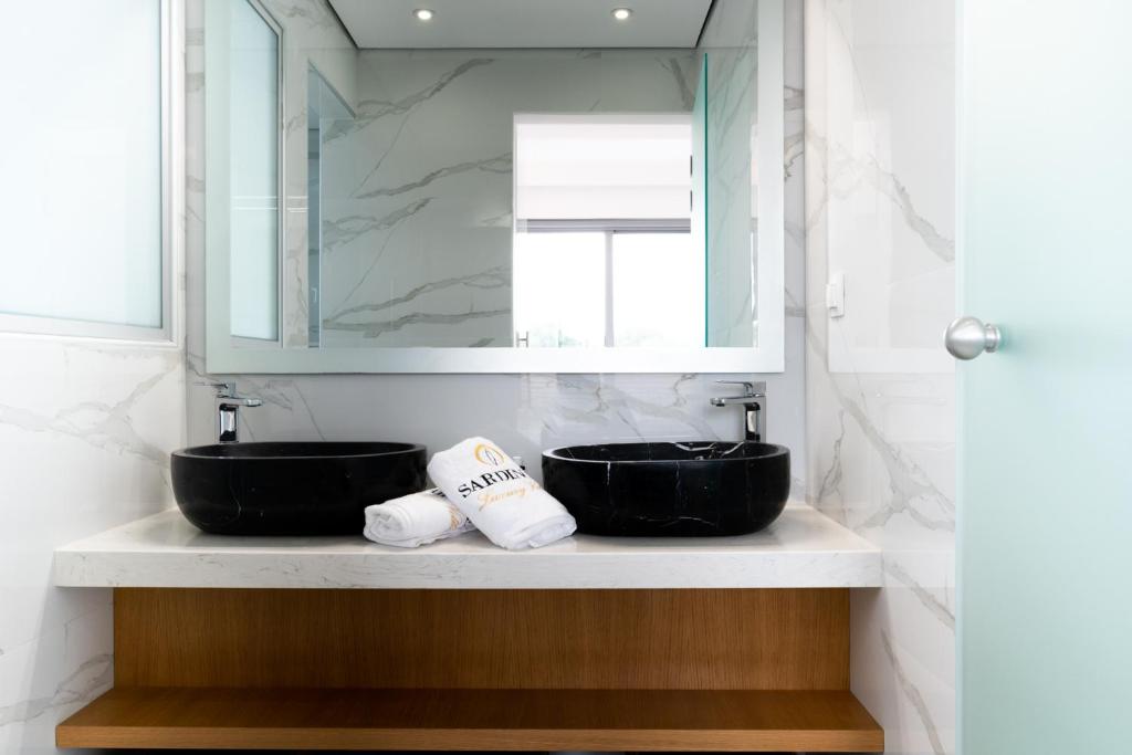 a bathroom with two black sinks and a mirror at Sardines Luxury Villas in Analipsi