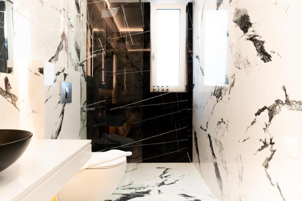 a bathroom with black and white marble walls and a toilet at Sardines Luxury Villas in Analipsi