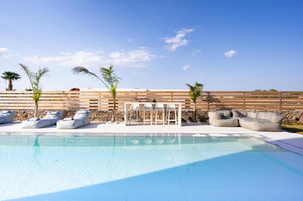 a swimming pool with blue water and palm trees at Sardines Luxury Villas in Analipsi