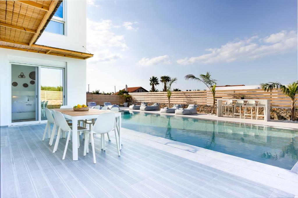 a patio with a table and chairs next to a swimming pool at Sardines Luxury Villas in Analipsi
