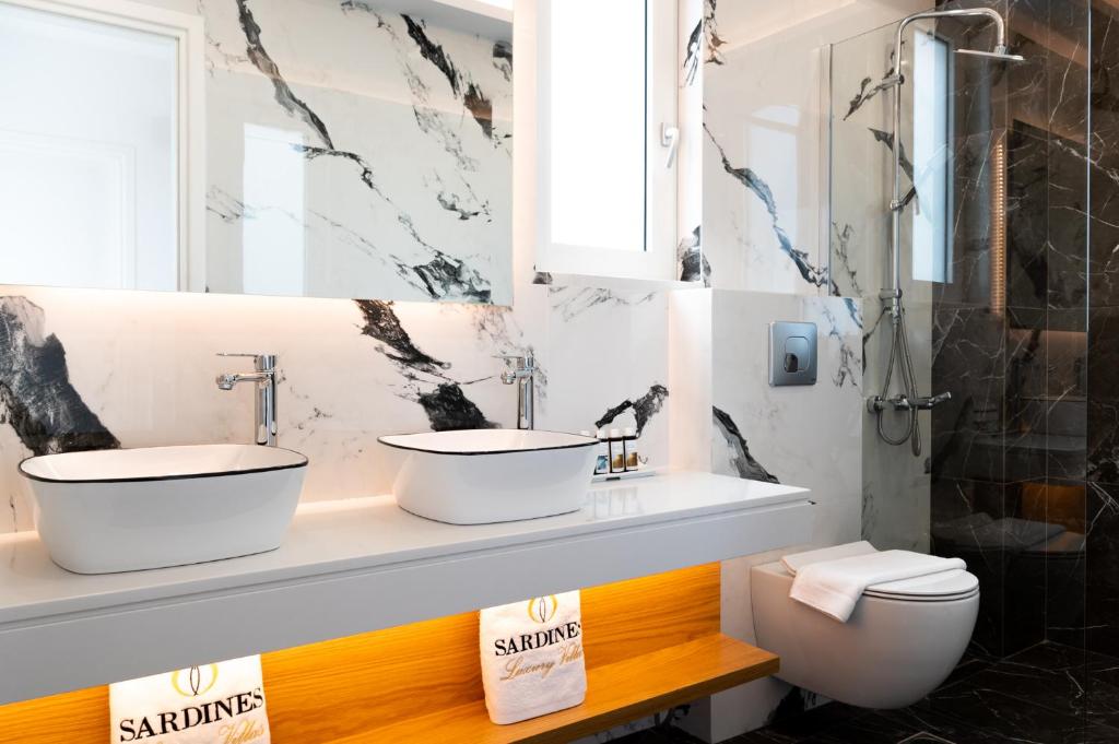 a bathroom with two sinks and a toilet at Sardines Luxury Villas in Analipsi
