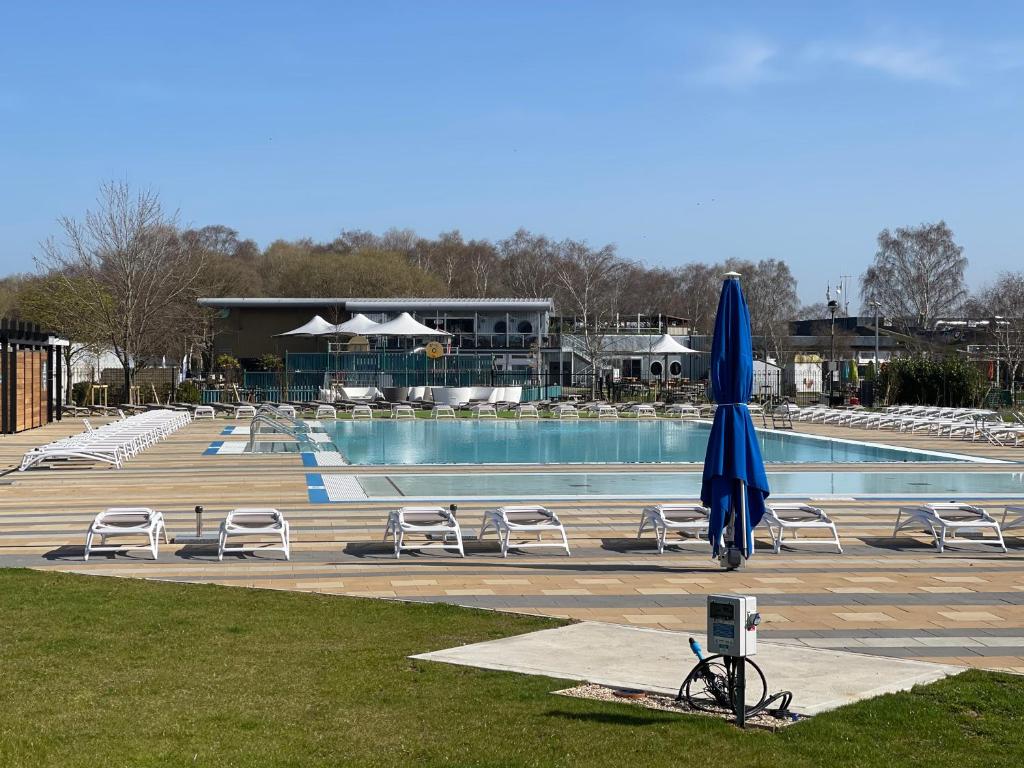 einen Pool mit Stühlen und einem blauen Sonnenschirm in der Unterkunft Holiday Home Breaks At Tattershall Lakes in Lincoln