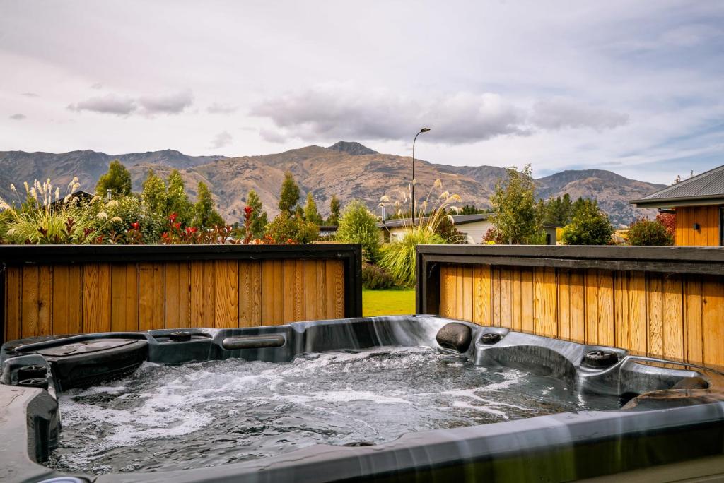 a hot tub in a backyard with mountains in the background at Erskine Place - Lake Hawea Holiday Home in Lake Hawea